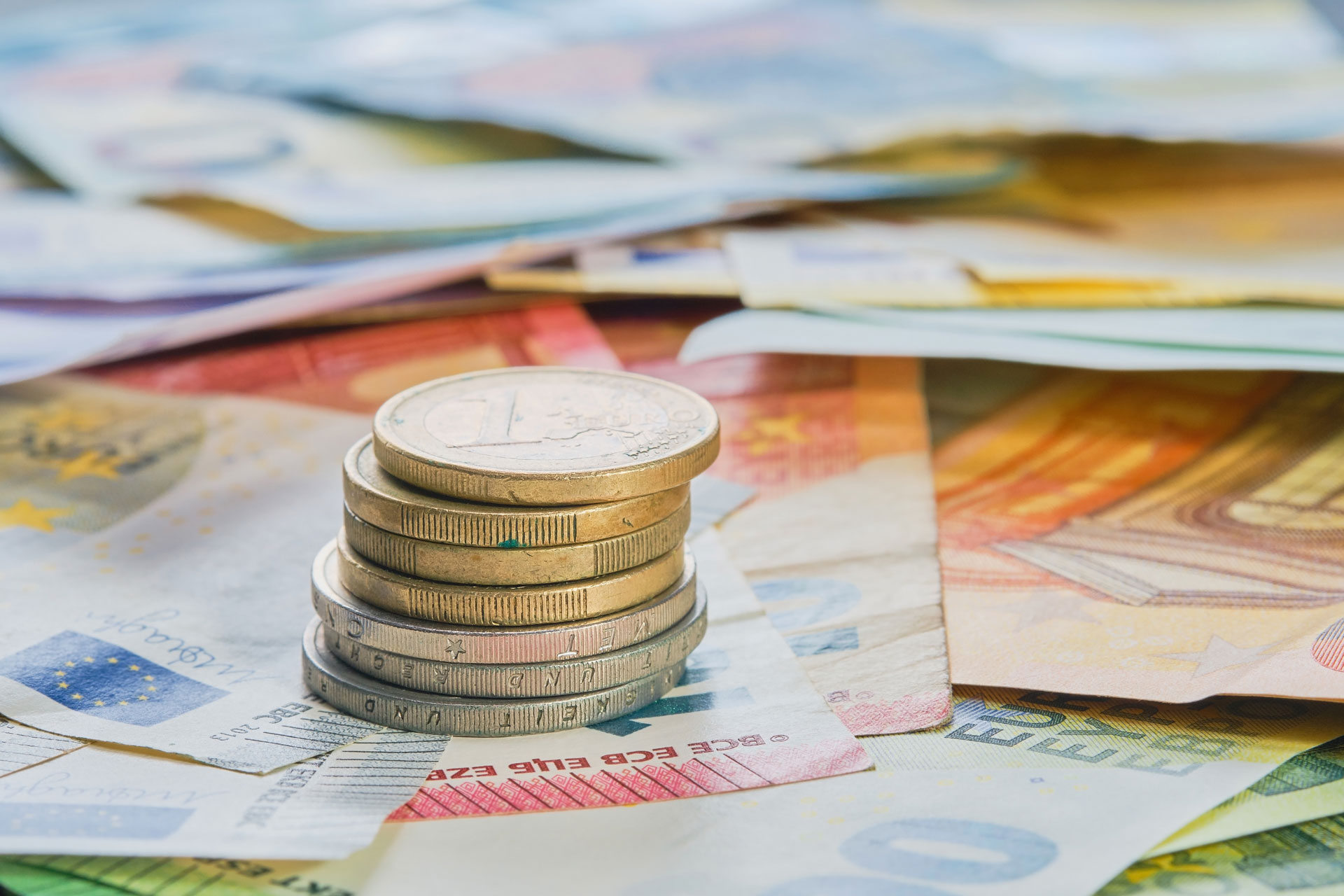 Gestapelte Euro-Münzen liegen auf Geldscheinen – Symbolmotiv für Geldleistungen und finanzielle Unterstützung durch das Jobcenter.